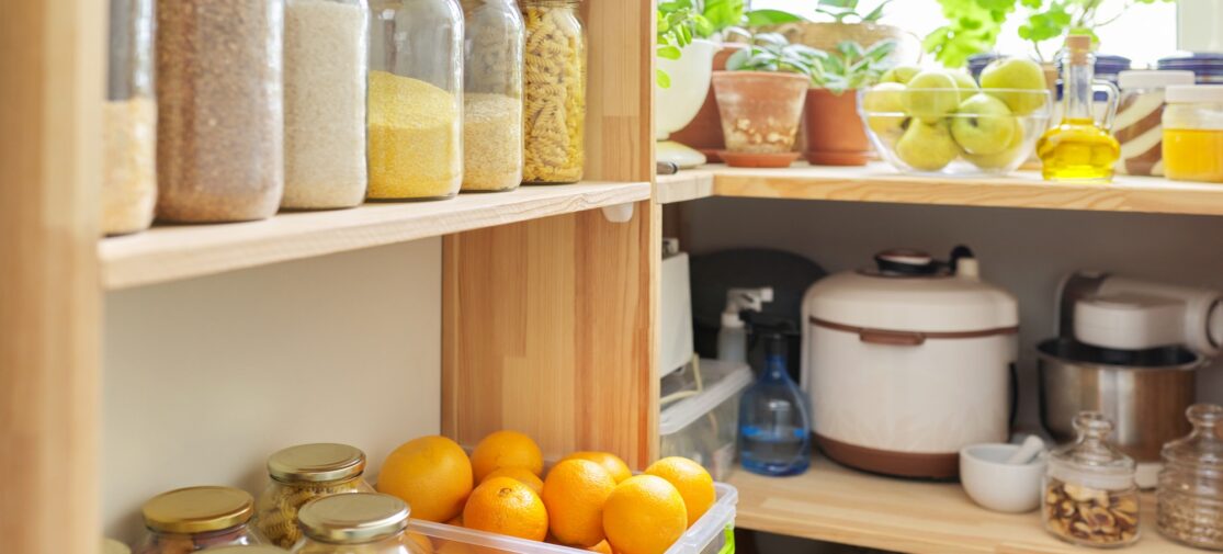 Spiżarnia kuchenna, drewniane półki ze słoikami i pojemnikami z żywnością, przechowywanie żywności.