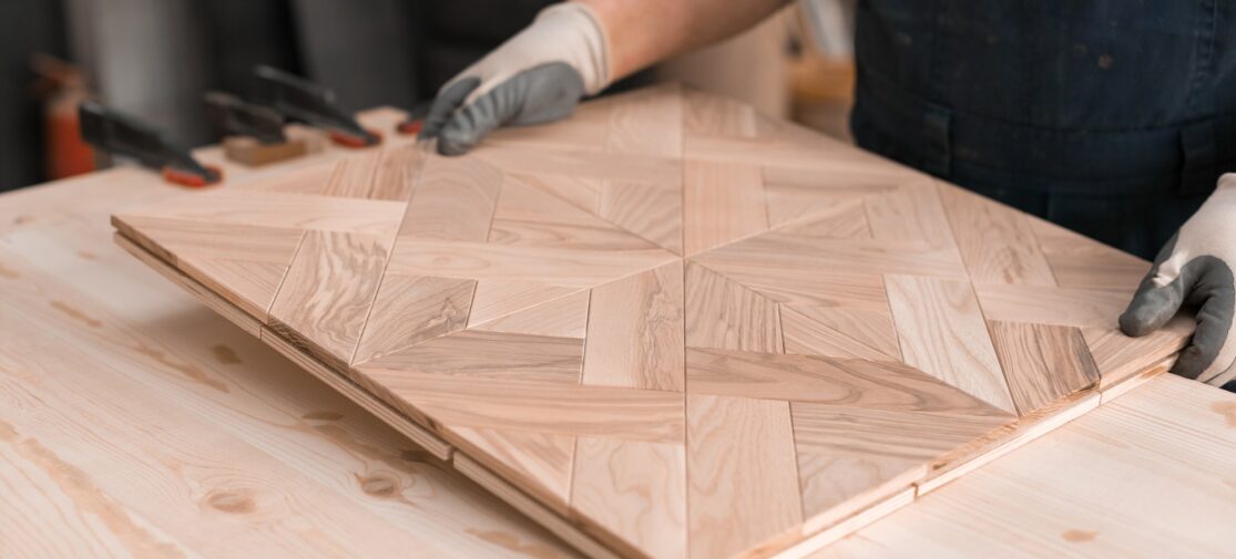 Mężczyzna trzymający drewniany panel podłogowy. Ręcznie wykonana produkcja podłóg